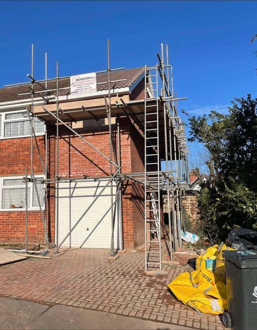 Two storey side extension under scaffold with Wonderwall site board