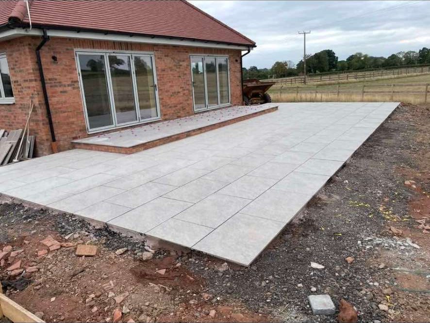 Grey porcelain patio and step laid outside a new brick bungalow