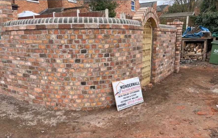 Curved reclaimed brick wall with arched gateway and rounded coping
